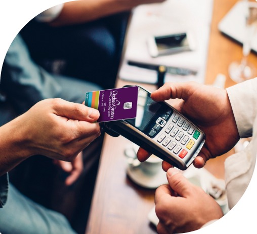 A man taps a purple Nebula Trust visa debit card to a payment machine