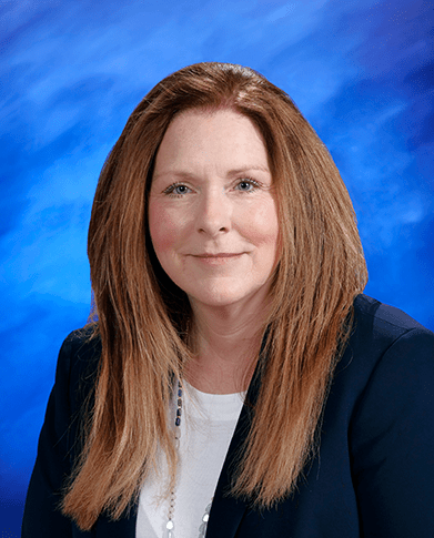 A studio portrait of Dawn Sandvoss with a bright blue textured background