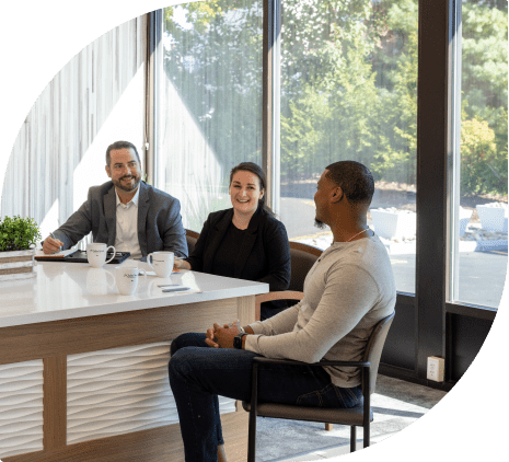 Three people in business attire sitting around a counter drinking coffee