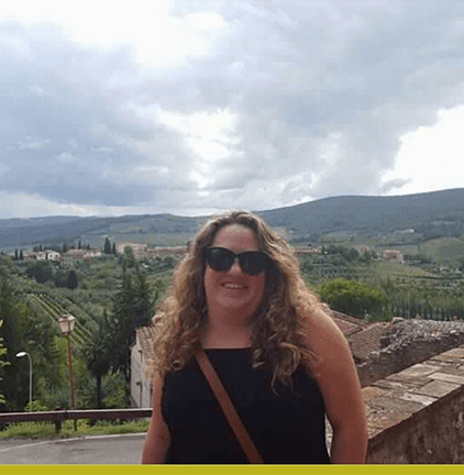 Krissa Beene smiling outside on a deck above a scenic green view of mountains