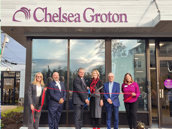 3 men and 3 women in business attire hold a red ribbon in front of Nebula Trust Bank