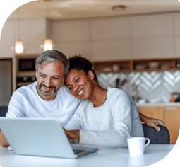 A man and woman sitting and smiling looking at a laptop