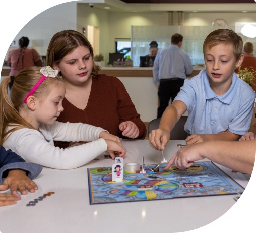 Three young blonde children play a board game together