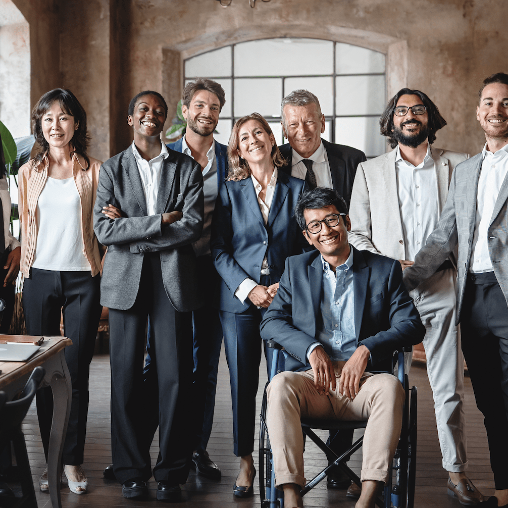 A diverse group of 8 smiling people in grey and blue business attire