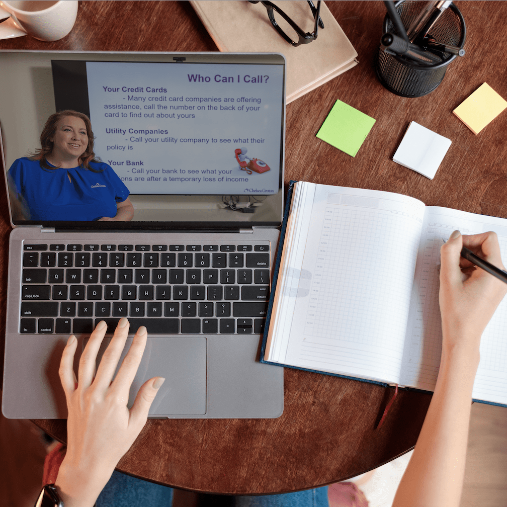 A woman's hands use a laptop with an online learning slide and take notes in notebook